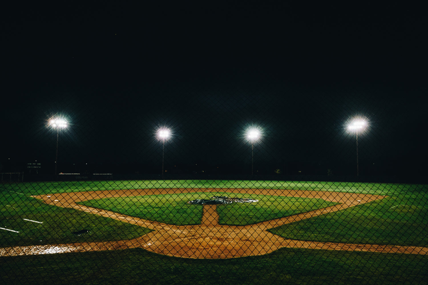 4 lights in the outfield over youth baseball ball park during the night